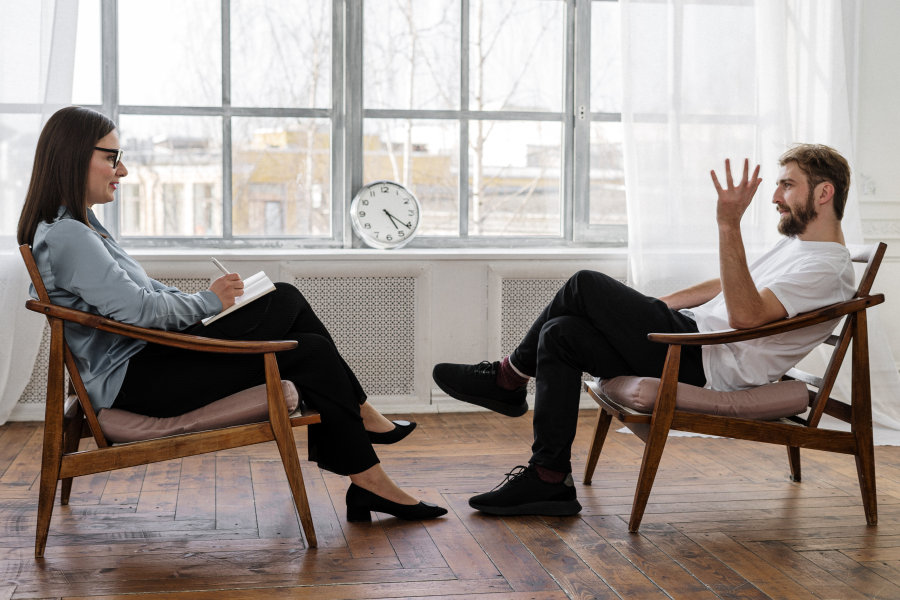 zdjęcie przedstawia rozmowę dwoje ludzi siedzących na krzesłach