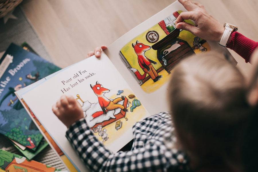 zdjęcie przedstawia dziecko oglądającą obrazki w książce